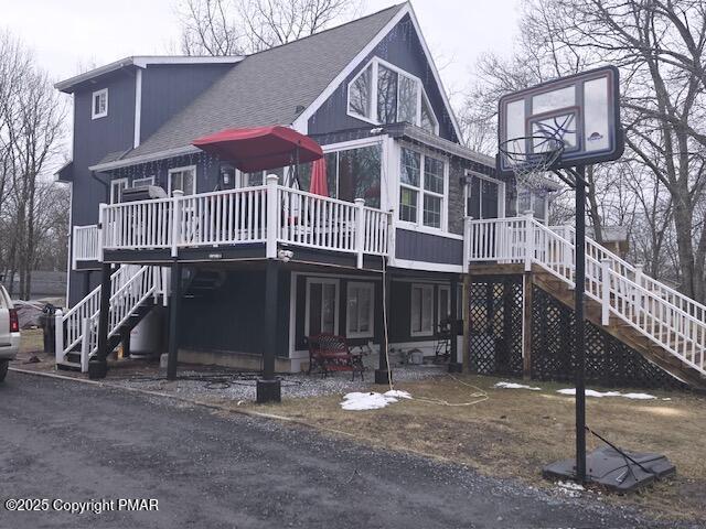 exterior space featuring a shingled roof, stairway, and a wooden deck