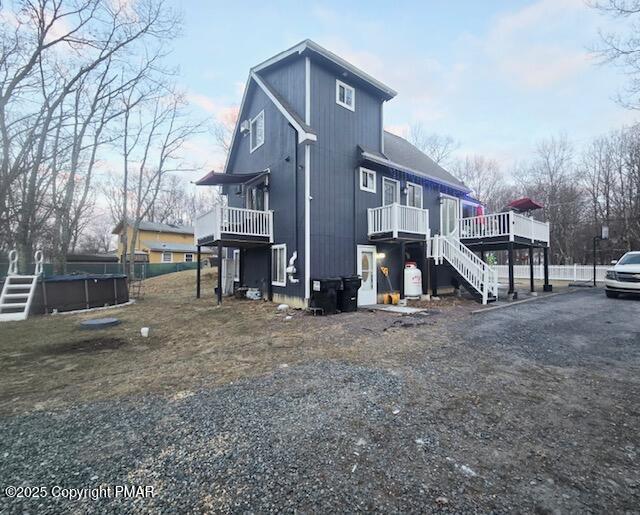 view of property exterior with stairway, a wooden deck, and an outdoor pool