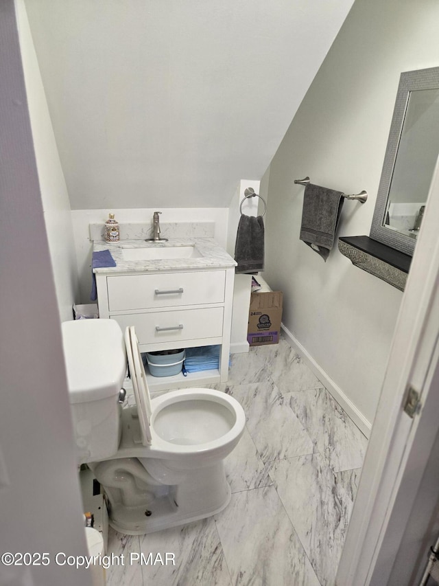 half bathroom with marble finish floor, lofted ceiling, toilet, vanity, and baseboards