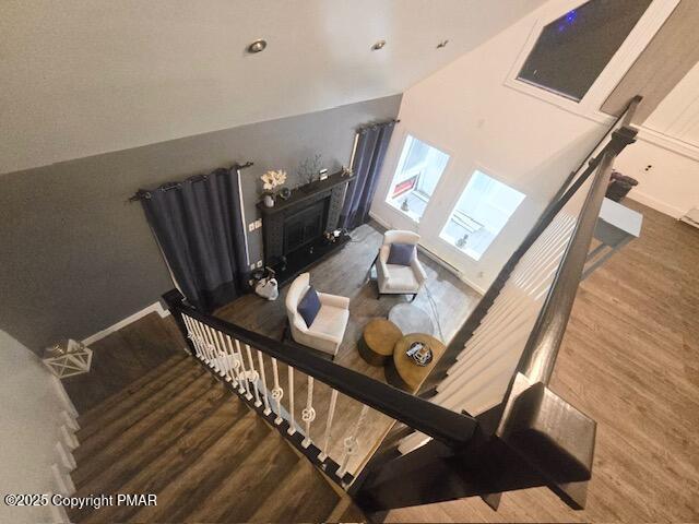 stairway with a fireplace, baseboards, and wood finished floors