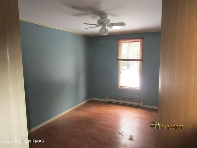 empty room featuring a ceiling fan, baseboards, baseboard heating, and wood finished floors