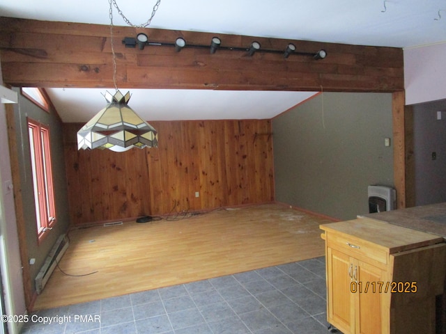 interior space with a baseboard heating unit, vaulted ceiling with beams, wooden walls, and wood finished floors