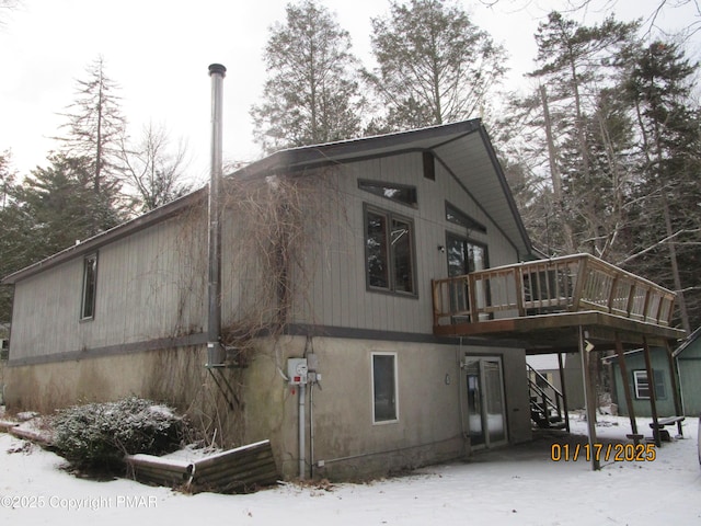 snow covered property featuring a deck and stairway