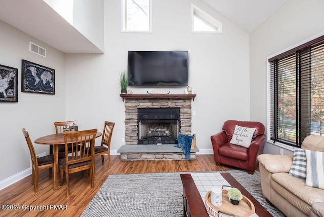 living area with baseboards, visible vents, lofted ceiling, wood finished floors, and a fireplace