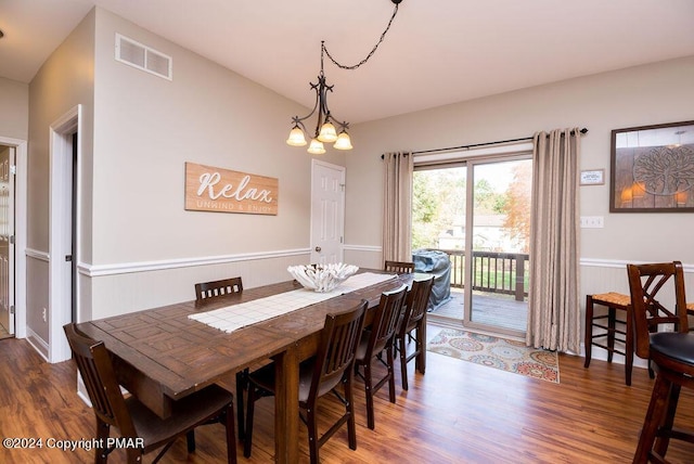 dining space with visible vents, a notable chandelier, and wood finished floors