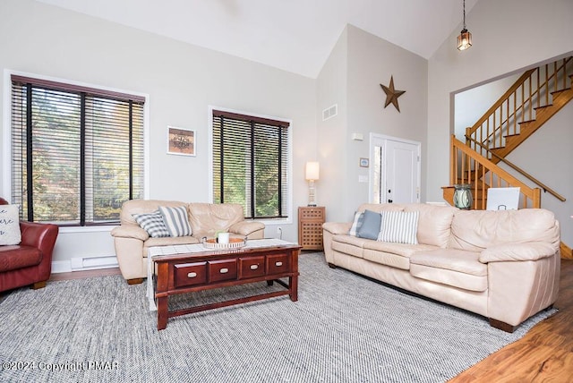 living room featuring high vaulted ceiling, a baseboard radiator, wood finished floors, visible vents, and stairs