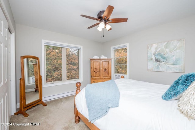 bedroom featuring multiple windows, a baseboard heating unit, a closet, and light colored carpet