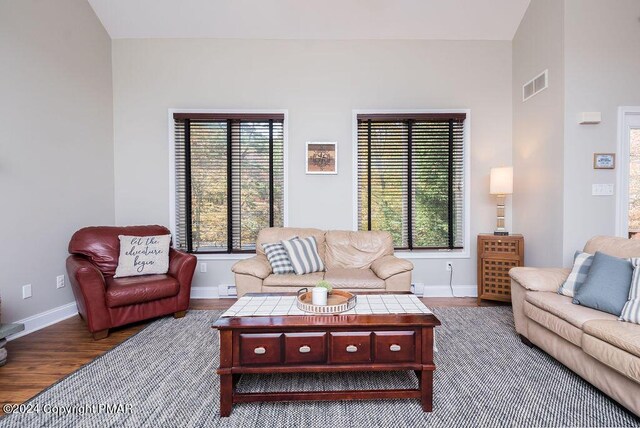 living room featuring baseboards, visible vents, a wealth of natural light, and wood finished floors