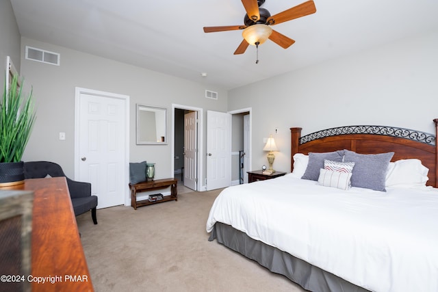 bedroom with light carpet, visible vents, and a ceiling fan