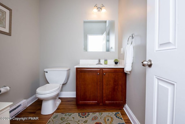 bathroom with toilet, baseboard heating, wood finished floors, and vanity