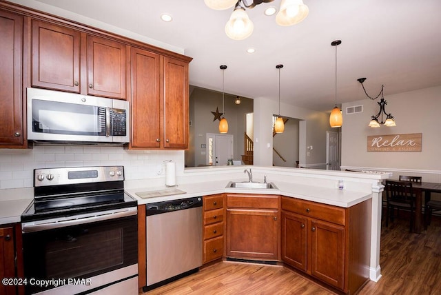 kitchen featuring stainless steel appliances, light countertops, visible vents, a sink, and a peninsula