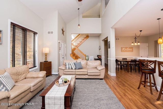 living area with stairs, high vaulted ceiling, light wood-style flooring, and visible vents