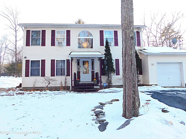 view of front of house with aphalt driveway, cooling unit, and an attached garage