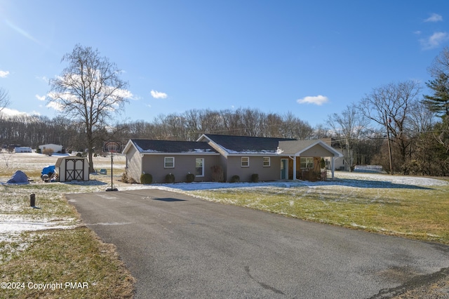 ranch-style home featuring an outdoor structure, driveway, a front lawn, and a storage unit