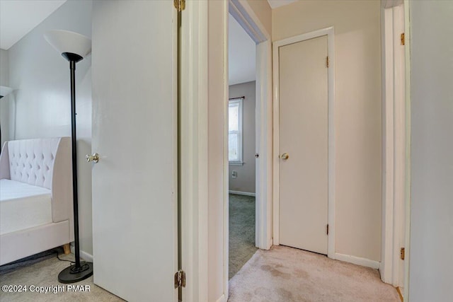 corridor featuring light carpet and baseboards