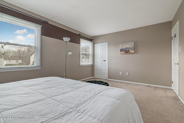 carpeted bedroom with a closet and baseboards