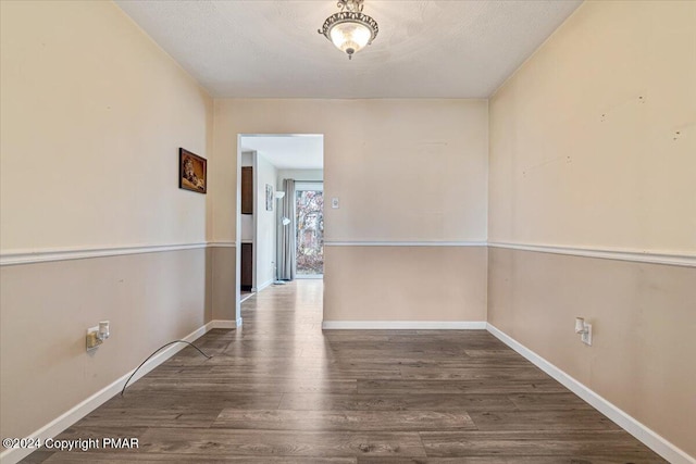 spare room with baseboards and wood finished floors