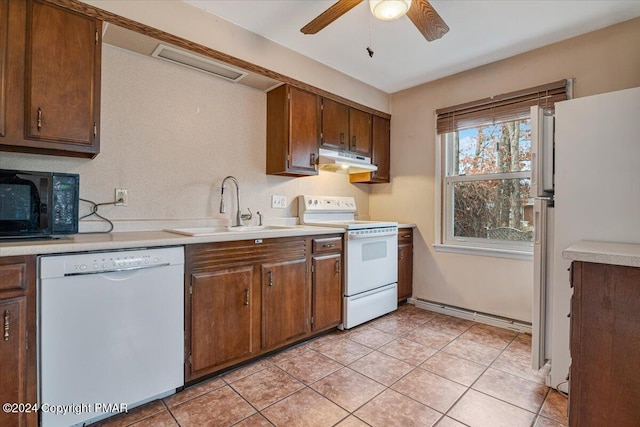 kitchen featuring light tile patterned floors, under cabinet range hood, white appliances, a sink, and light countertops