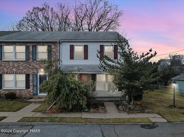 view of front of home featuring brick siding and a lawn