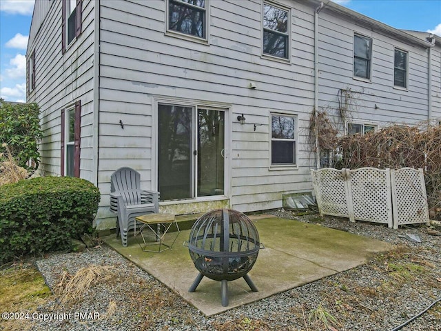 back of property with a fire pit and a patio