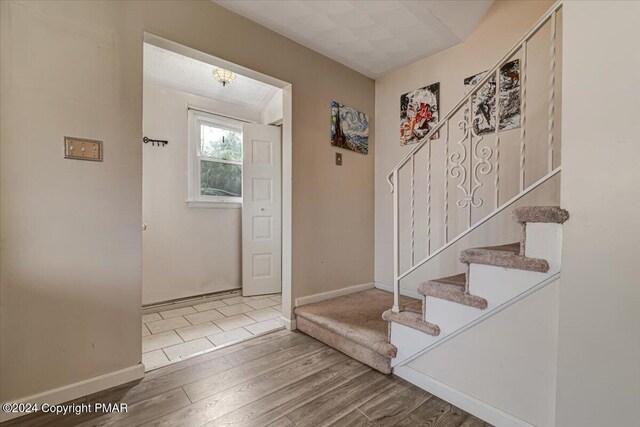 entryway featuring baseboards, stairway, and wood finished floors