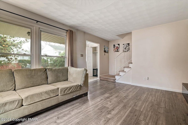 unfurnished living room with stairway, baseboards, and wood finished floors