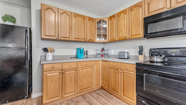 9148 Brandywine Dr, Tobyhanna, PA 18466 - kitchen with black appliances, light wood finished floors, light countertops, and glass insert cabinets