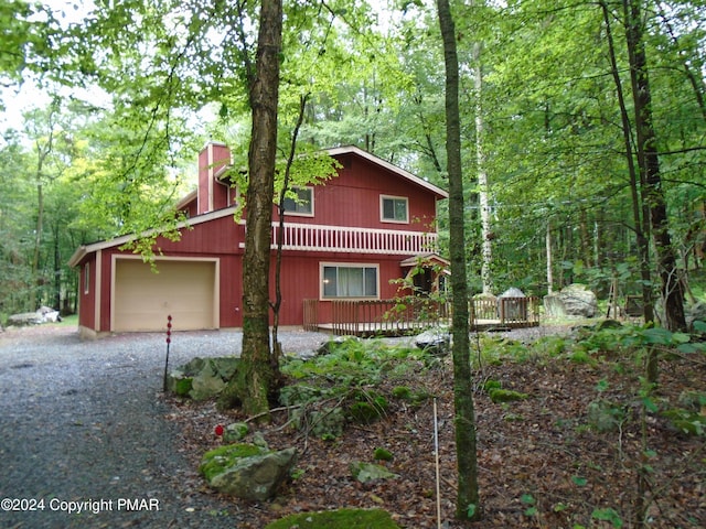 view of side of property featuring driveway, a chimney, and a forest view