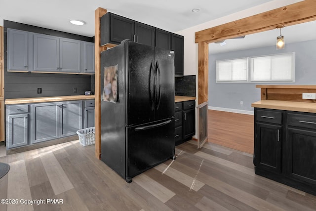 kitchen featuring light wood-style floors, freestanding refrigerator, and dark cabinets