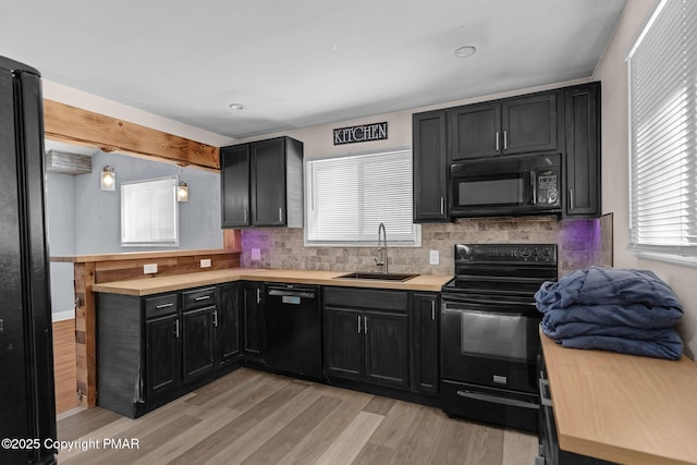 kitchen with tasteful backsplash, dark cabinets, light countertops, black appliances, and a sink