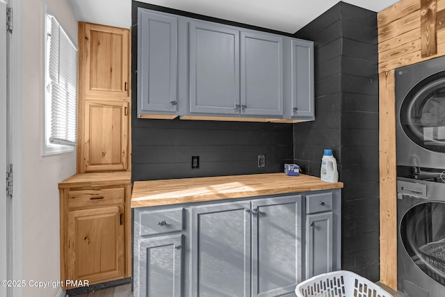 laundry room with cabinets and stacked washer and clothes dryer