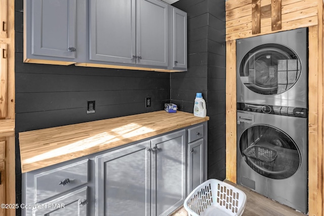 washroom featuring stacked washer and dryer and cabinet space