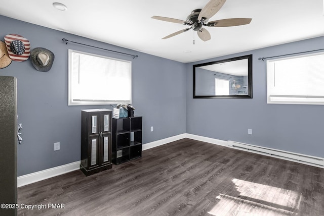 empty room with dark hardwood / wood-style flooring, a baseboard radiator, and ceiling fan