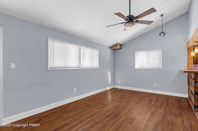 empty room with lofted ceiling, wood finished floors, a ceiling fan, and baseboards