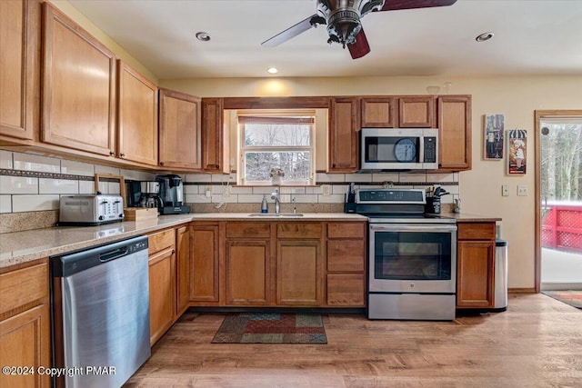 kitchen with tasteful backsplash, appliances with stainless steel finishes, light countertops, and light wood-type flooring