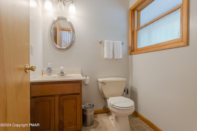 half bath featuring baseboards, vanity, toilet, and tile patterned floors