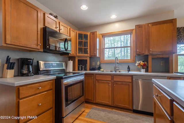 kitchen featuring brown cabinetry, stainless steel appliances, a sink, and light countertops