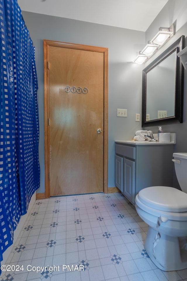 bathroom with toilet, baseboards, and vanity