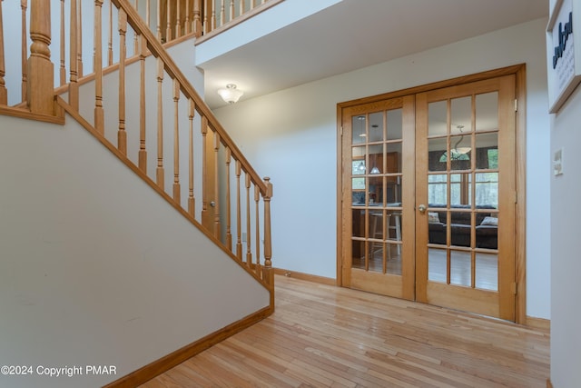 stairway with baseboards, wood finished floors, and french doors