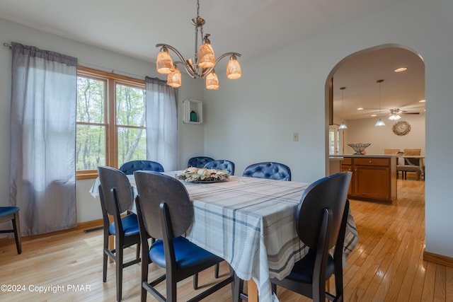 dining room featuring arched walkways, light wood-style flooring, recessed lighting, and ceiling fan with notable chandelier