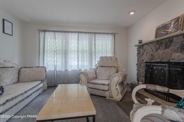 carpeted living room with a stone fireplace