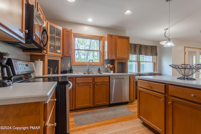 kitchen with stainless steel appliances, brown cabinetry, plenty of natural light, and a sink