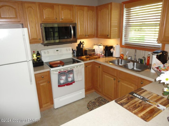 kitchen featuring light countertops, white appliances, light floors, and a sink