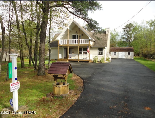 view of front of home featuring aphalt driveway, a front yard, and a balcony