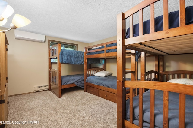 bedroom with a baseboard heating unit, an AC wall unit, a textured ceiling, and carpet