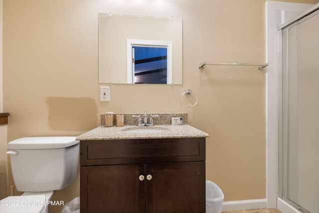 full bath with toilet, a stall shower, vanity, and baseboards