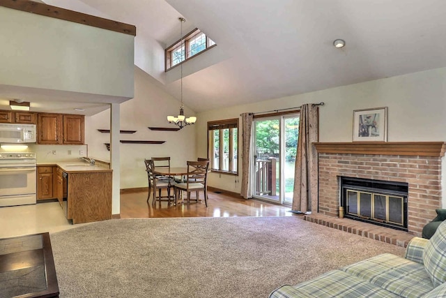 living area with healthy amount of natural light, a brick fireplace, high vaulted ceiling, a chandelier, and baseboards