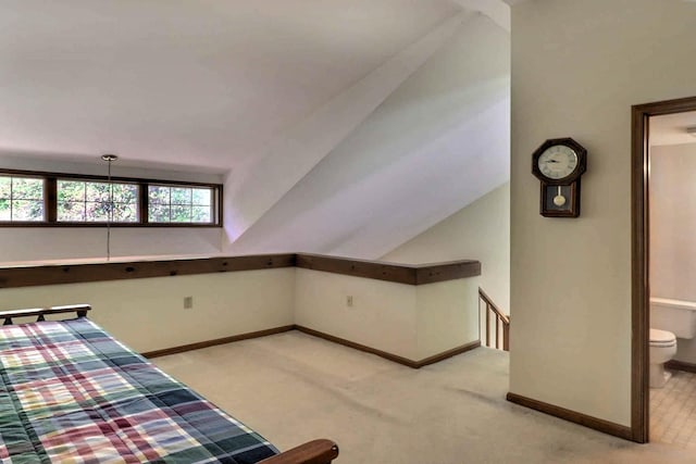 unfurnished bedroom with light colored carpet, baseboards, vaulted ceiling, and ensuite bath