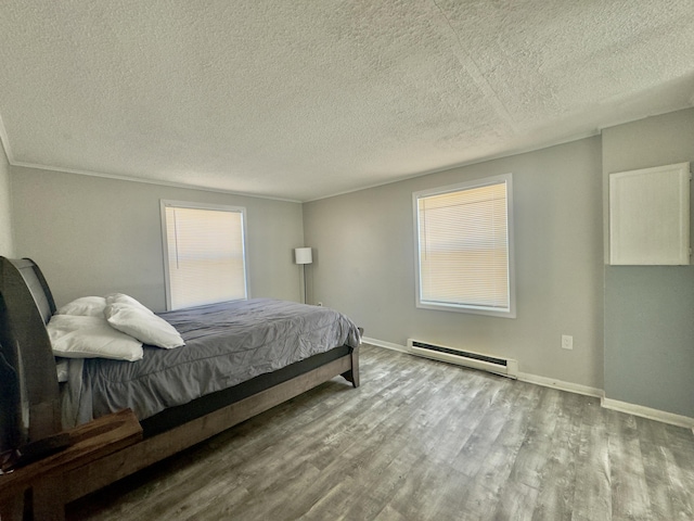 bedroom with a baseboard radiator, baseboards, a textured ceiling, and wood finished floors