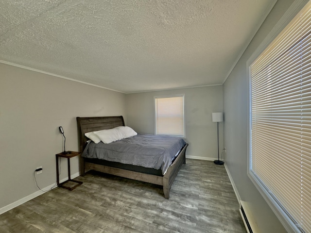 bedroom featuring a baseboard heating unit, crown molding, baseboards, wood finished floors, and a textured ceiling